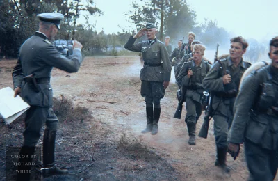 wojna - Grupa niemieckich piechurów maszerująca po polnej drodze, podczas gdy ich dow...