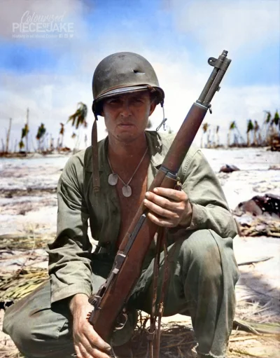 wojna - Amerykański żołnierz piechoty morskiej z dziurą w hełmie pozuje z karabinem M...