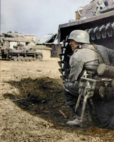 wojna - Niemiecki żołnierz z 14 Dywizji Pancernej przykucnął za czołgiem Panzer III w...