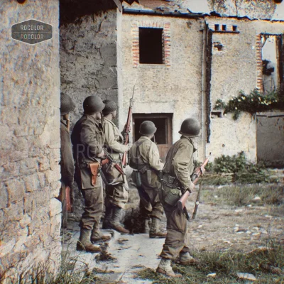 wojna - Amerykańscy żołnierze zatrzymują się ostrożnie obok budynku, szukając niemiec...