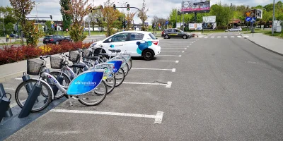 nieocenzurowany88 - Nowoczesne miasto. Na pierwszym planie rower miejski, dalej auto ...