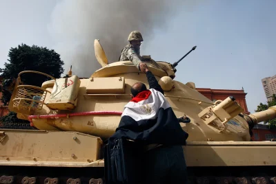 Talvisota - Protestujący owinięty w egipską flagę wspina się na czołg, aby podać rękę...