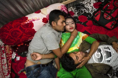 myrmekochoria - Papia, 18, with two customers on the bed in the Kandapara brothel. He...