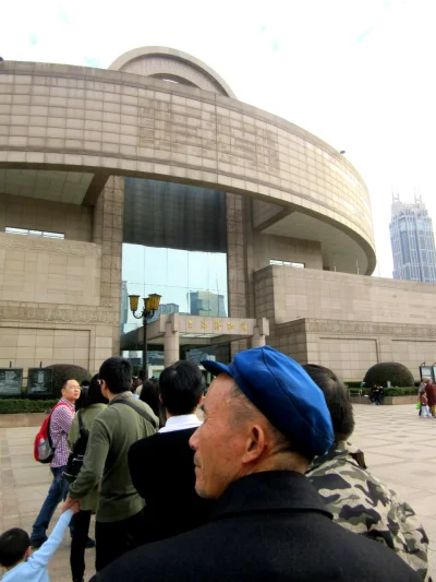 Dwadziescia_jeden - Starszy człowiek stojący w kolejce przed owalnym gmachem Muzeum S...