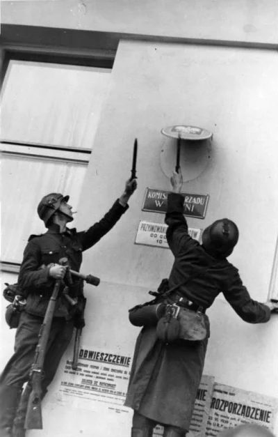 N.....h - Na zdjęciu dwóch niemieckich żołnierzy usuwa polskie godło ze ściany rządu....