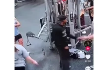 Kobieta na siłowni łapie mężczyznę za tyłek.