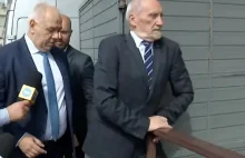 Macierewicz uciekając przed dziennikarzami próbuje przeskoczyć przez płot