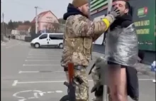 Ukraiński żołnierz spuszcza spodnie złapanym szabrownikom
