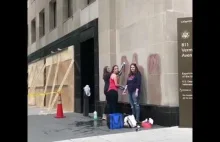 Trzy dziewczyny ścierają znak BLM namalowany na rogu budynku