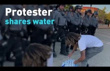 Czarny protestujący rozdaje wode policji i dziękuje im za służbe