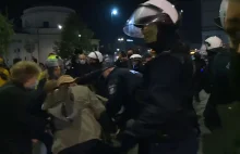 Policjant popycha starszą kobietę na proteście