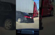 Ciężarówka jedzie z autem pod przyczepą