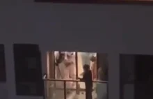 Chiny: Ludzie w białych kombinezonach szarpią się z człowiekiem na balkonie