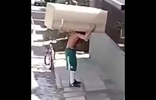 Silny mężczyzna wiezie lodówkę na rowerze