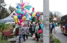 Człowiek idzie zapalić znicz... i przebija się między balonami i słodyczami