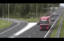 Policjant na motocyklu blokuje ciężarówkę na autostradzie.