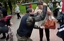 Rosyjski policjant pałuje kobietę.