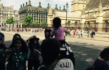 Mężczyzna chodzi obok brytyjskiego parlamentu w fladze ISIS