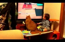 Dziecko i kot oglądają z wielkim zainteresowaniem filmik na telewizorze