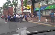 Ludzie ratujący człowieka uwięzionego pod samochodem