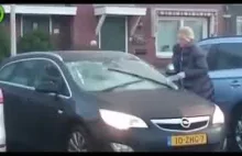 Kobieta usuwa lód z szyby samochodu