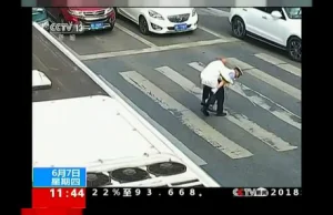 Pomocny policjant przenosi staruszka przez ruchliwą ulicę
