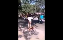 Indyski policjant przeprowadza psiaka przez ruchliwą ulicę