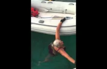 Starsza pani pokazuje jak się dostać na ponton będąc w wodzie