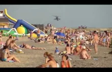 Niski przelot wojskowego śmigłowca nad zatłoczoną plażą