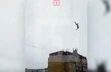 Chłop próbuje przespacerować się po kablach między budynkami na wysokości 30m.