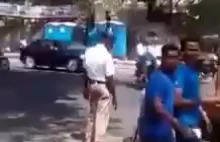 Policjant kierujący ruchem zatrzymuje pojazdy żeby pies mógł przejść przez drogę