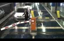 Kobieta chce wjechać na parking, ale na drodze jest szlaban...