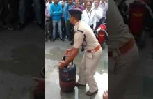 Opalony policjant pokazuje jak zgasić płonącą butlę LPG
